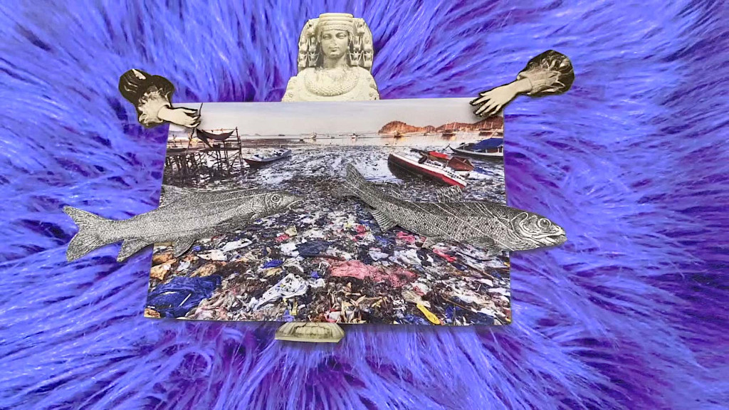 Screenshot aus einem Stop-Motion-Collage-Film. Eine aus Papier ausgeschnittene Collage liegt auf einem Videohintergrund aus lila Kunstfell. Im Zentrum ein Foto eines verm&uuml;llten Ufers mit Booten, &uuml;berlagert von zwei schwarz-wei&szlig;en gezeichneten Fischen. Um das Foto sind weitere Bildelemente arrangiert: Oben eine Skulptur mit aufwendigem Kopfschmuck, erinnernd an Fruchtbarkeitsdarstellungen wie die Artemis von Ephesos; links und rechts ragen barock anmutende Arme ins Bild; unten ist der Sockel der Skulptur zu sehen. Die surreale Komposition thematisiert Umweltzerst&ouml;rung, Weiblichkeit und Mythologie.